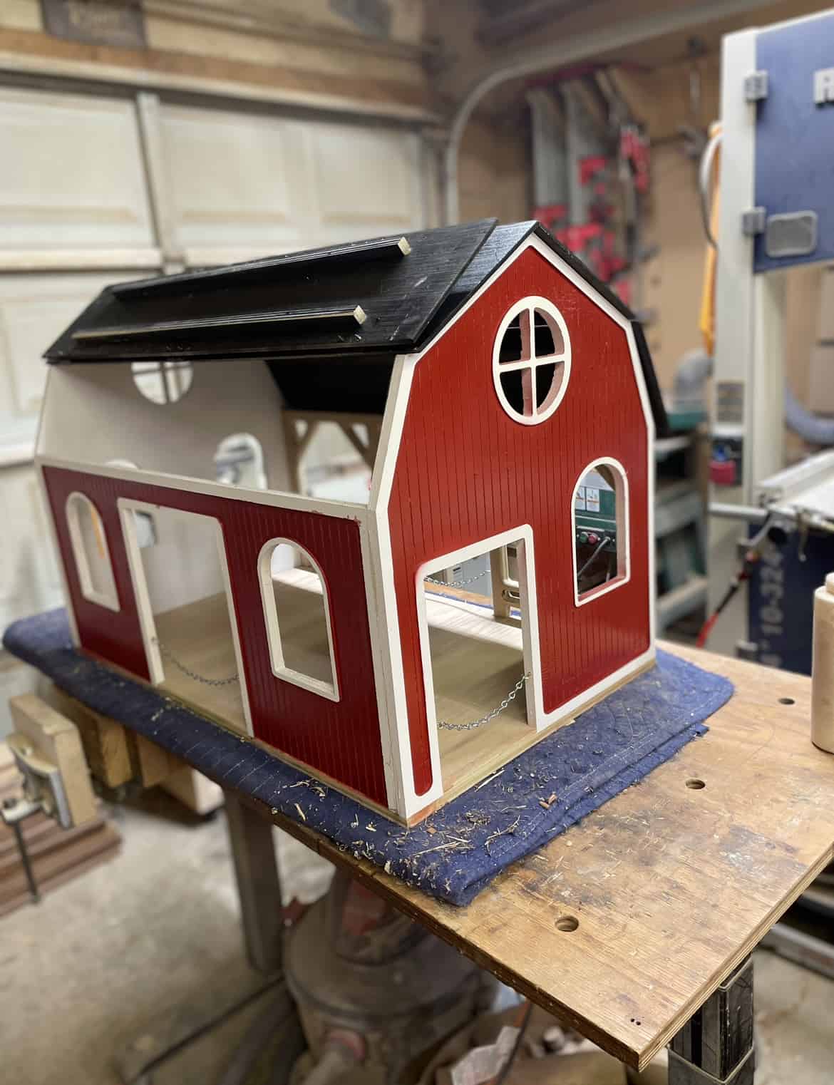 Handmade toy wooden barn. Red siding with black roof. roof lifted open for access. gambrel roof